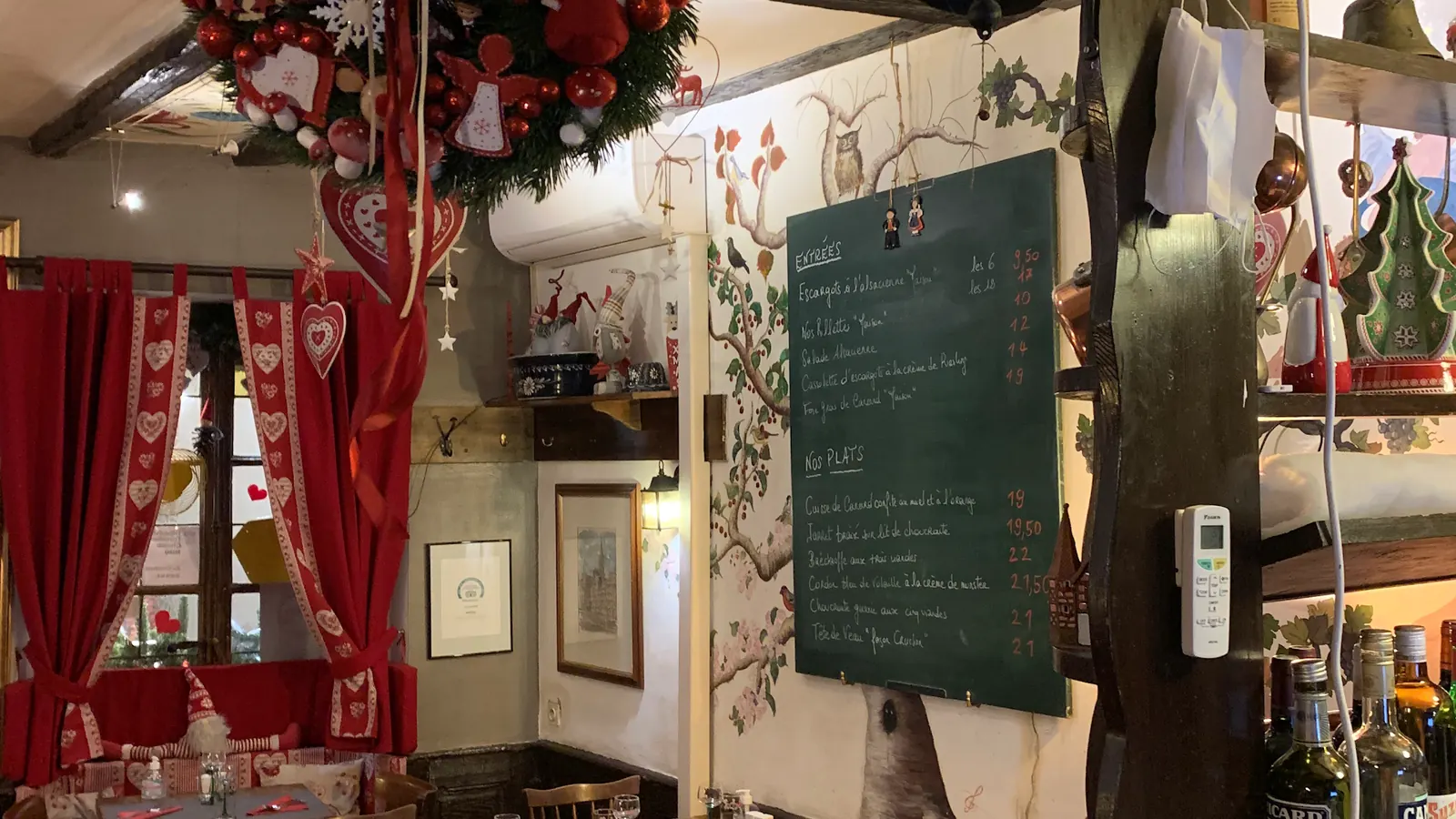 La salle du Cruchon : fresque peinte, ardoise du jour, rideaux rouges à cœurs